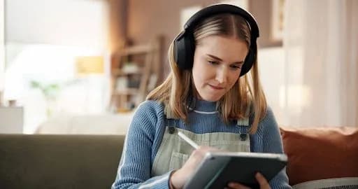 a young girl studying hard while listening to music in headphones
